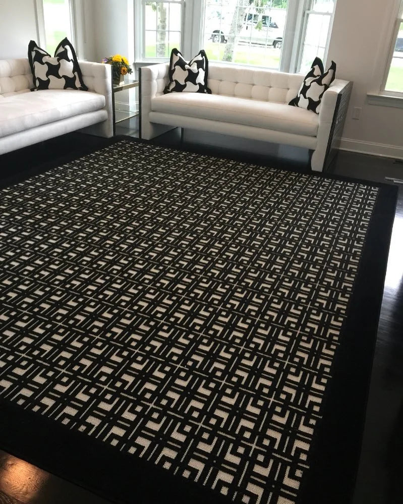Modern living room featuring a custom black and white geometric area rug with white sofas and contemporary décor.