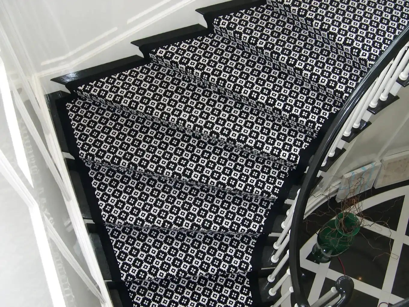 Black and white patterned stair runner on a curved staircase.