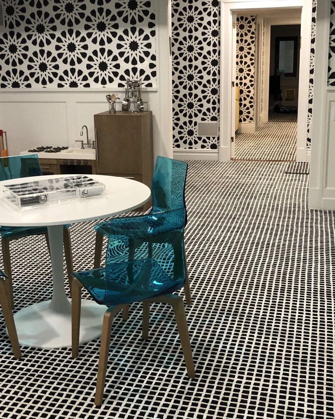 Custom black and white patterned carpet installation in a modern home with designer wallpaper and contemporary dining area.