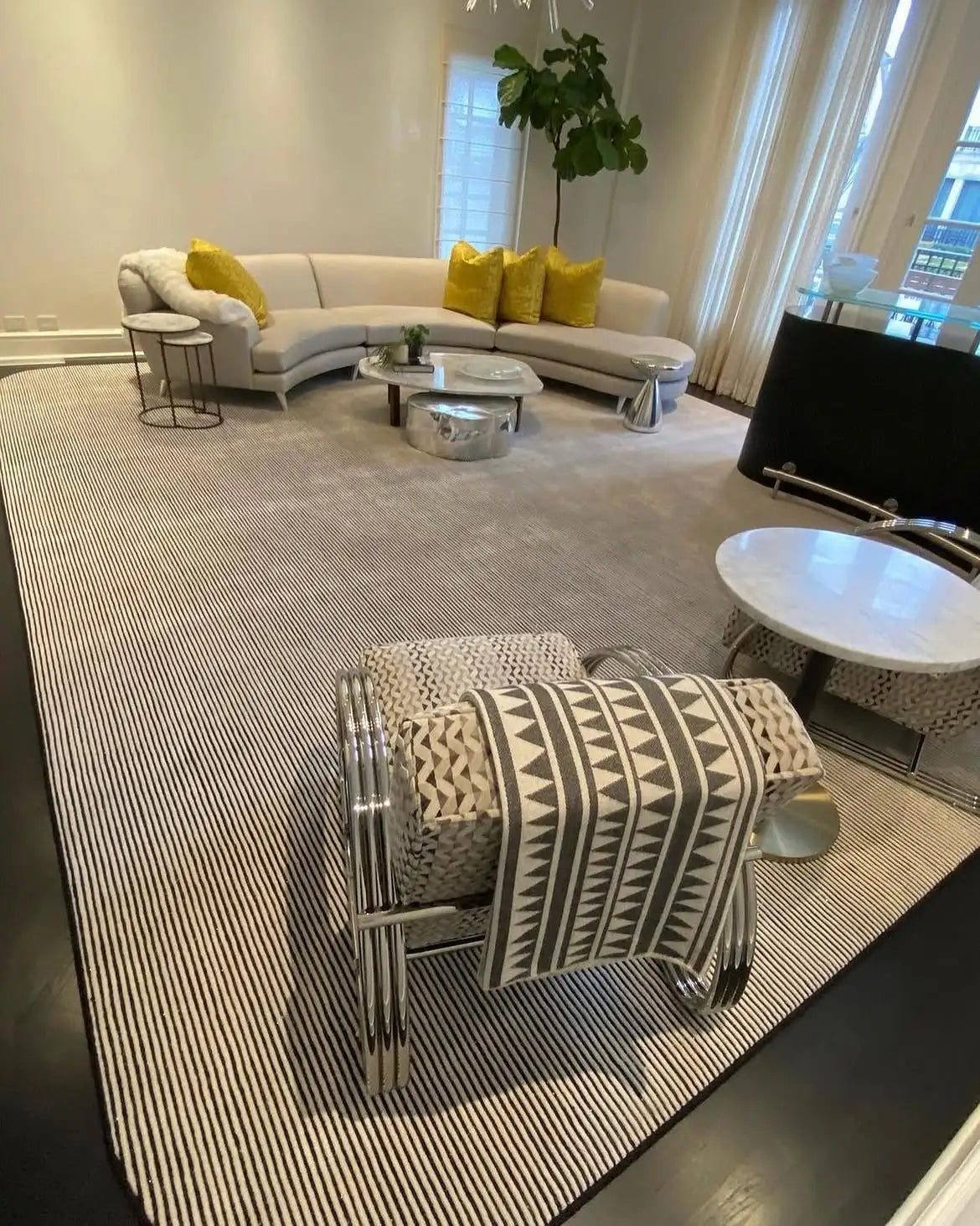 Custom striped area rug in a contemporary luxury living room with curved sectional seating.