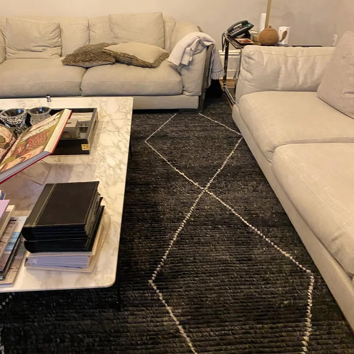 Luxury black area rug with geometric pattern in a modern living room.