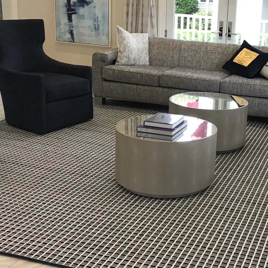 Modern living room with a luxury custom area rug, gray sofa, black accent chair, and contemporary coffee tables in Monmouth County, NJ