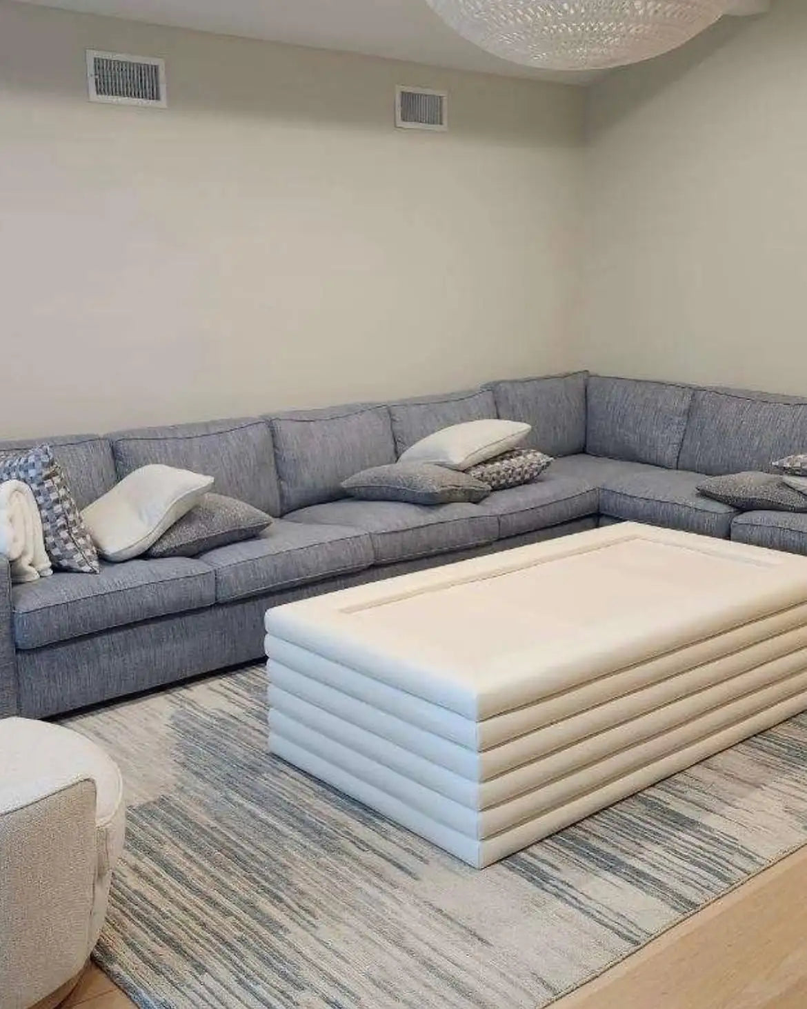 Modern blue and gray designer area rug in a spacious family room with sectional seating.
