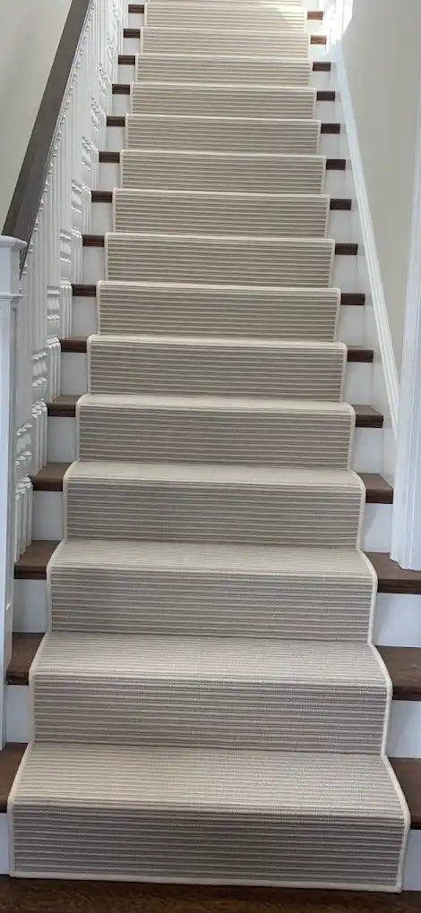 Neutral striped custom stair runner on a wood staircase.