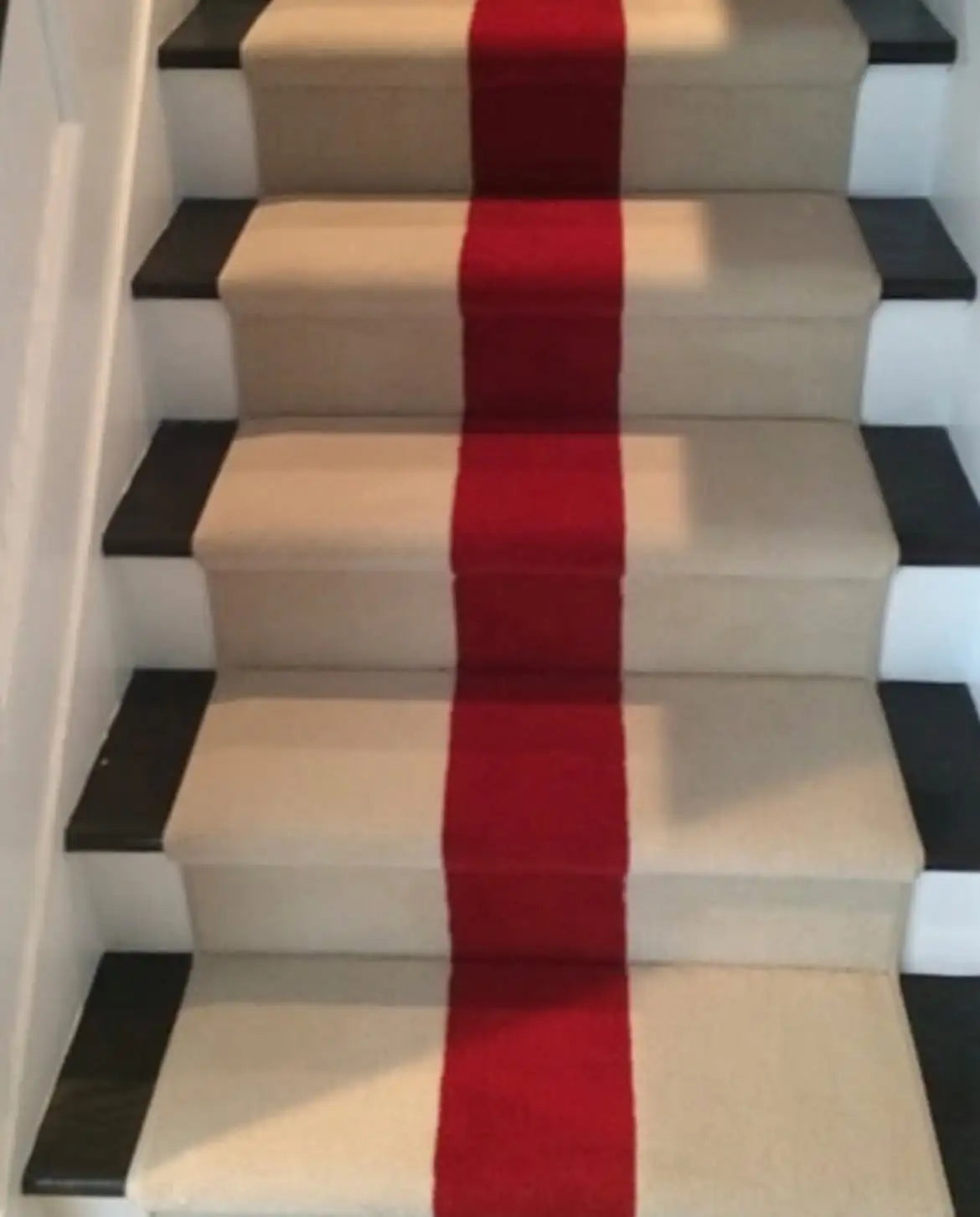 Red custom stair runner professionally installed on hardwood staircase in a New York City home.