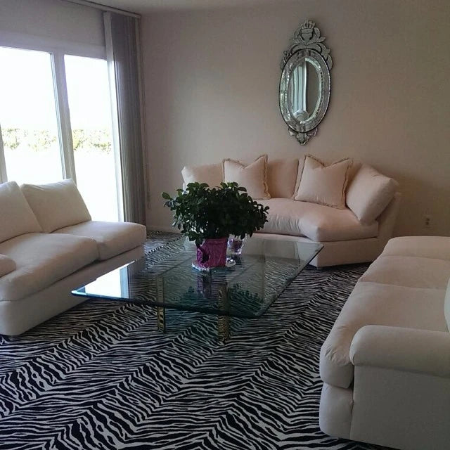 Custom zebra pattern area rug in a modern living room with white sofas, glass coffee table, and contemporary décor.